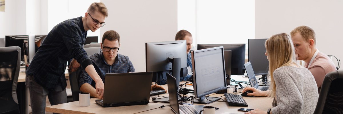 Full concentration at work. Group of young business people working and communicating while sitting at the office desk together with colleagues sitting in the background